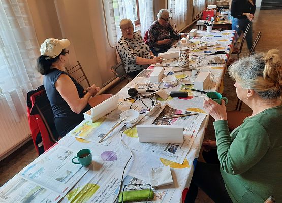 Kobiety siedzące przy stoliku i wykonujące pracę plastyczną