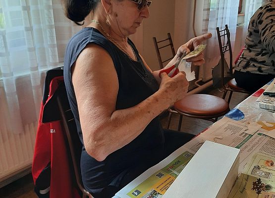 Kobieta siedząca przy stoliku i wykonująca pracę plastyczną