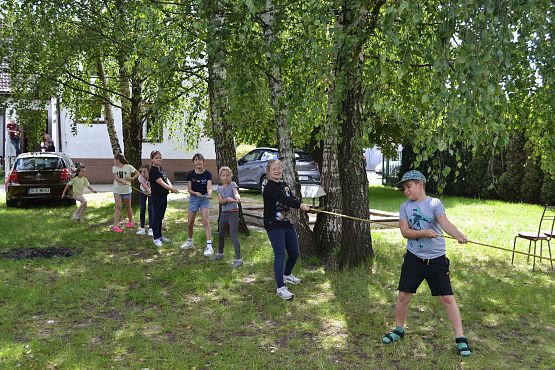 Dzieci podczas zabawy na podwórku przeciągają linę