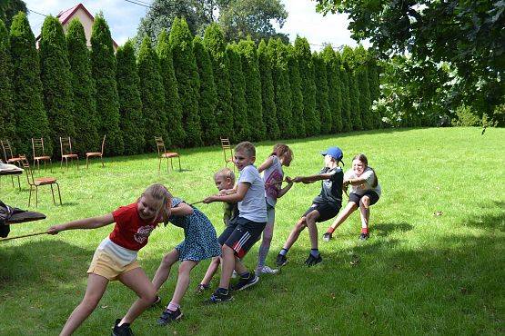Dzieci podczas zabawy na podwórku przeciągają linę