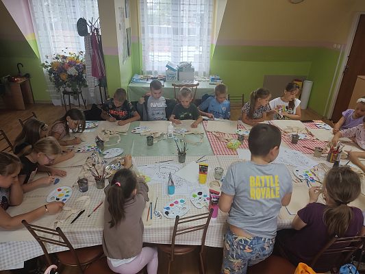 Grupa dzieci podczas ozdabiania materiałowych toreb