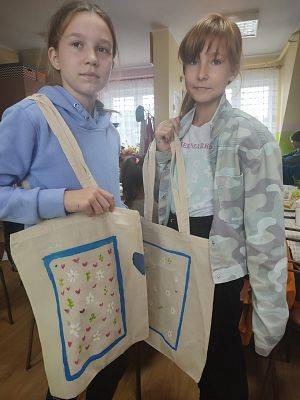 Dwie dziewczynki pozują do zdjęcia z ozdobionymi torbami
