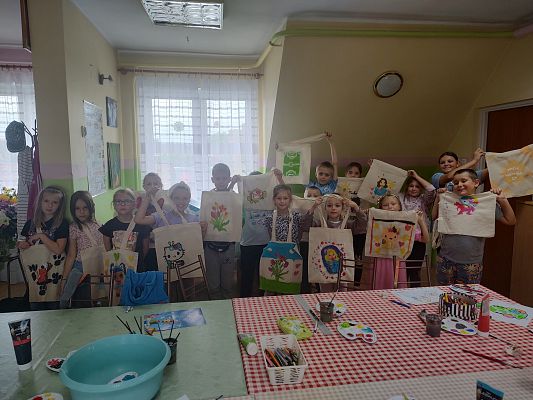 Grupa dzieci pozuje do zdjęcia z ozdobionymi torbami