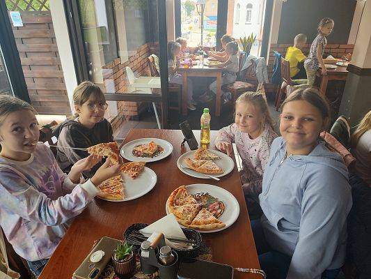 Dzieci pozują do zdjęcia podczas jedzenia pizzy