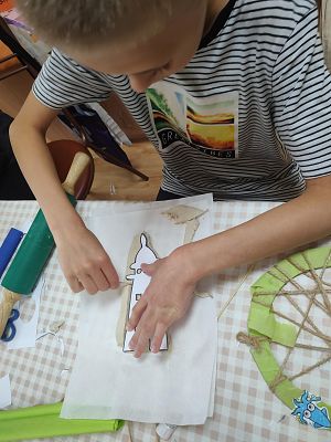 Na zdjęciu chłopiec wycinający wzór latarni w glinie samoutwardzalnej