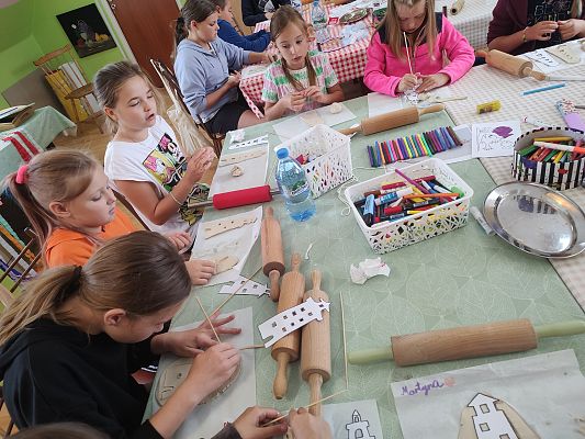 Na zdjęciu dzieci wycinające wzór latarni w glinie samoutwardzalnej