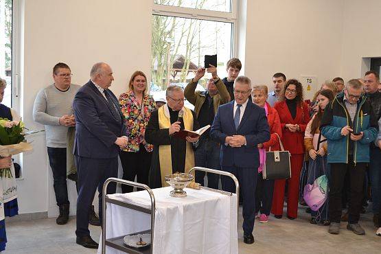 Ksiądz święci salę oraz przybyłych gości wodą święconą.