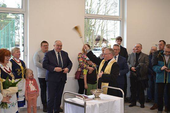 Ksiądz święci salę oraz przybyłych gości wodą święconą.