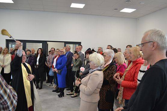 Ksiądz święci salę oraz przybyłych gości wodą święconą.