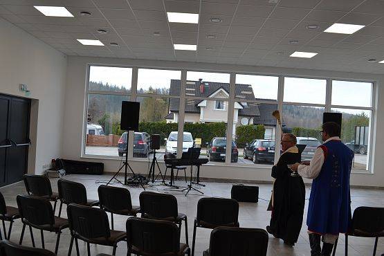 Ksiądz święci salę oraz przybyłych gości wodą święconą.