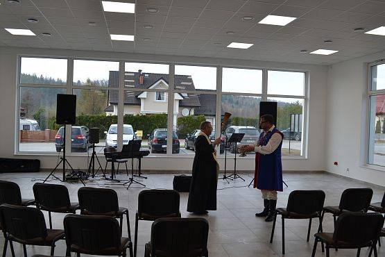 Ksiądz święci salę oraz przybyłych gości wodą święconą.