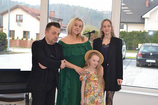 Wspólne zdjęcie wykonawców utworów na tle okien sali.