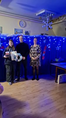 Na zdjęciu są trzy osoby: wręczający nagrody oraz uczestnik konkursu.