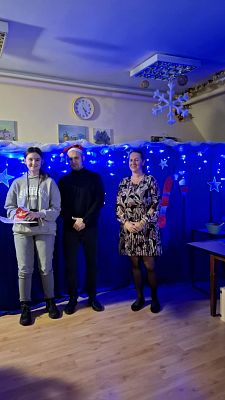 Na zdjęciu są trzy osoby: wręczający nagrody oraz uczestnik konkursu.