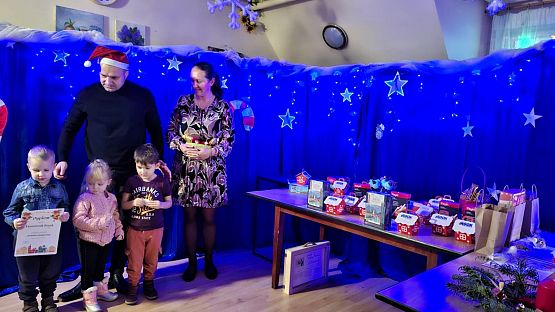 Na zdjęciu są dwie osoby dorosłe oraz troje dzieci: wręczający nagrody oraz uczestnicy konkursu.