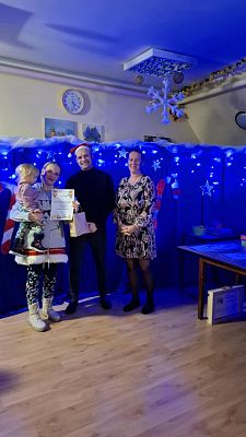 Na zdjęciu są trzy osoby: wręczający nagrody oraz uczestnik konkursu.