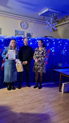 Na zdjęciu są trzy osoby: wręczający nagrody oraz uczestnik konkursu.