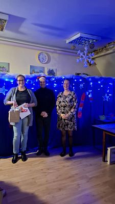 Na zdjęciu są trzy osoby: wręczający nagrody oraz uczestnik konkursu.