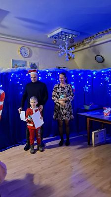 Na zdjęciu są trzy osoby: wręczający nagrody oraz uczestnik konkursu.