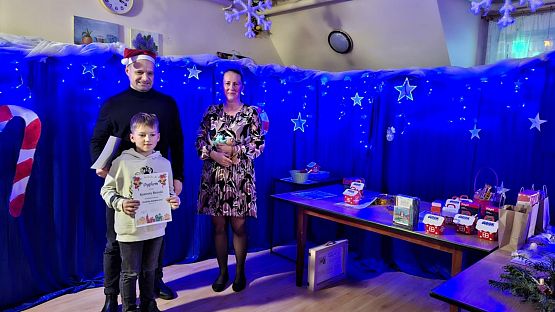 Na zdjęciu są trzy osoby: wręczający nagrody oraz uczestnik konkursu.