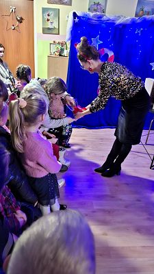 Na zdjęciu Pani Dyrektor rozdaje dzieciom świąteczne naklejki.